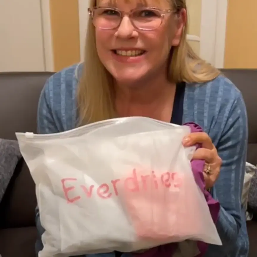 Person holding a clear bag labeled 'Everdries' with a smile.