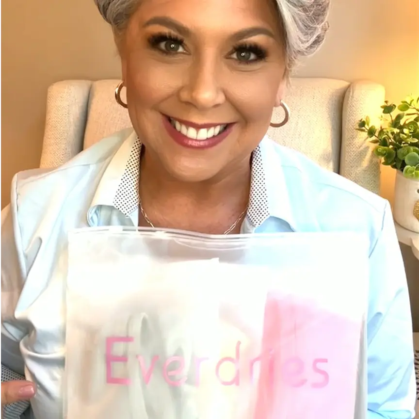 Smiling person holding a package labeled 'Everdries' in a cozy room.