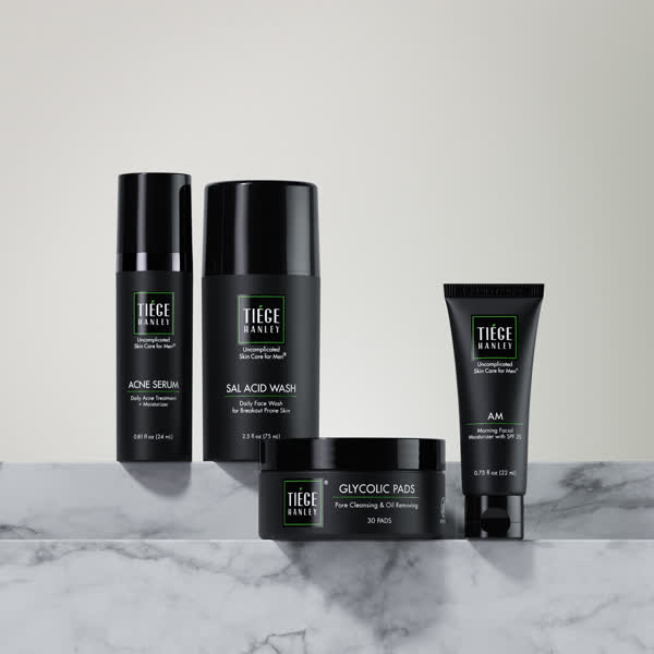 Five skincare products on a marble surface.