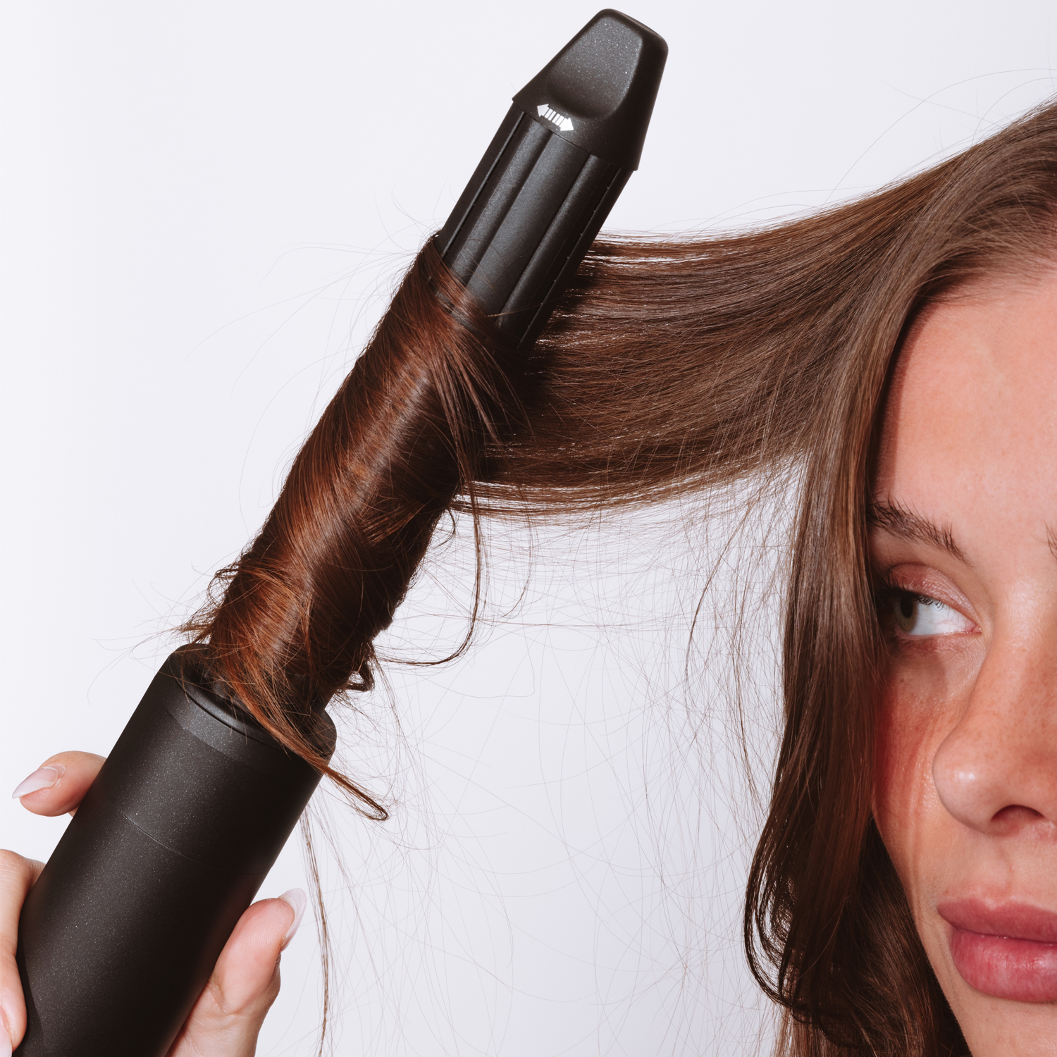 Close-up of a woman curling her hair with a curling iron.