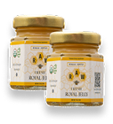 Two small glass jars of Raw Fresh Royal Jelly with gold-colored lids and white and yellow labels.