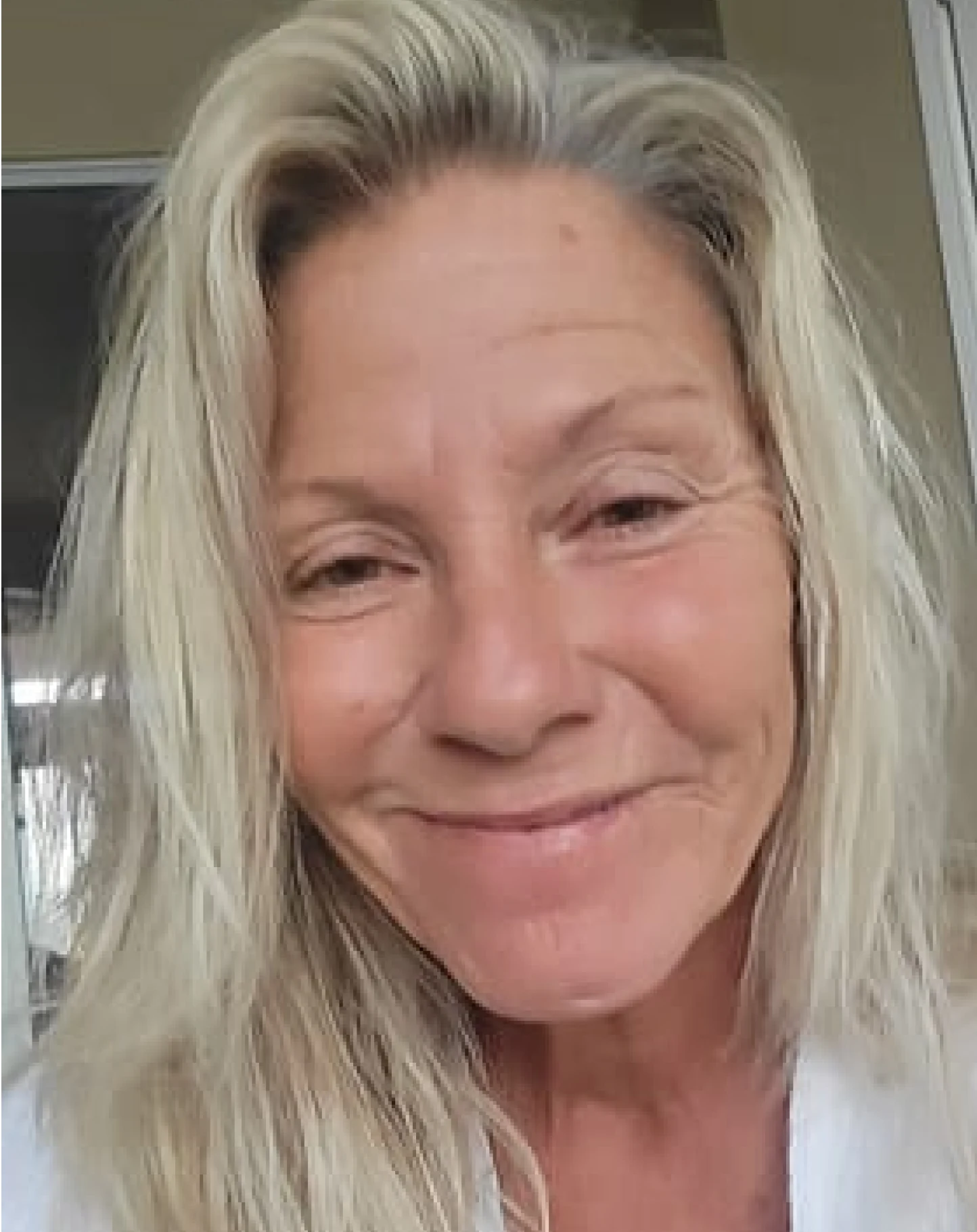 Smiling person with long blonde hair in a casual setting.