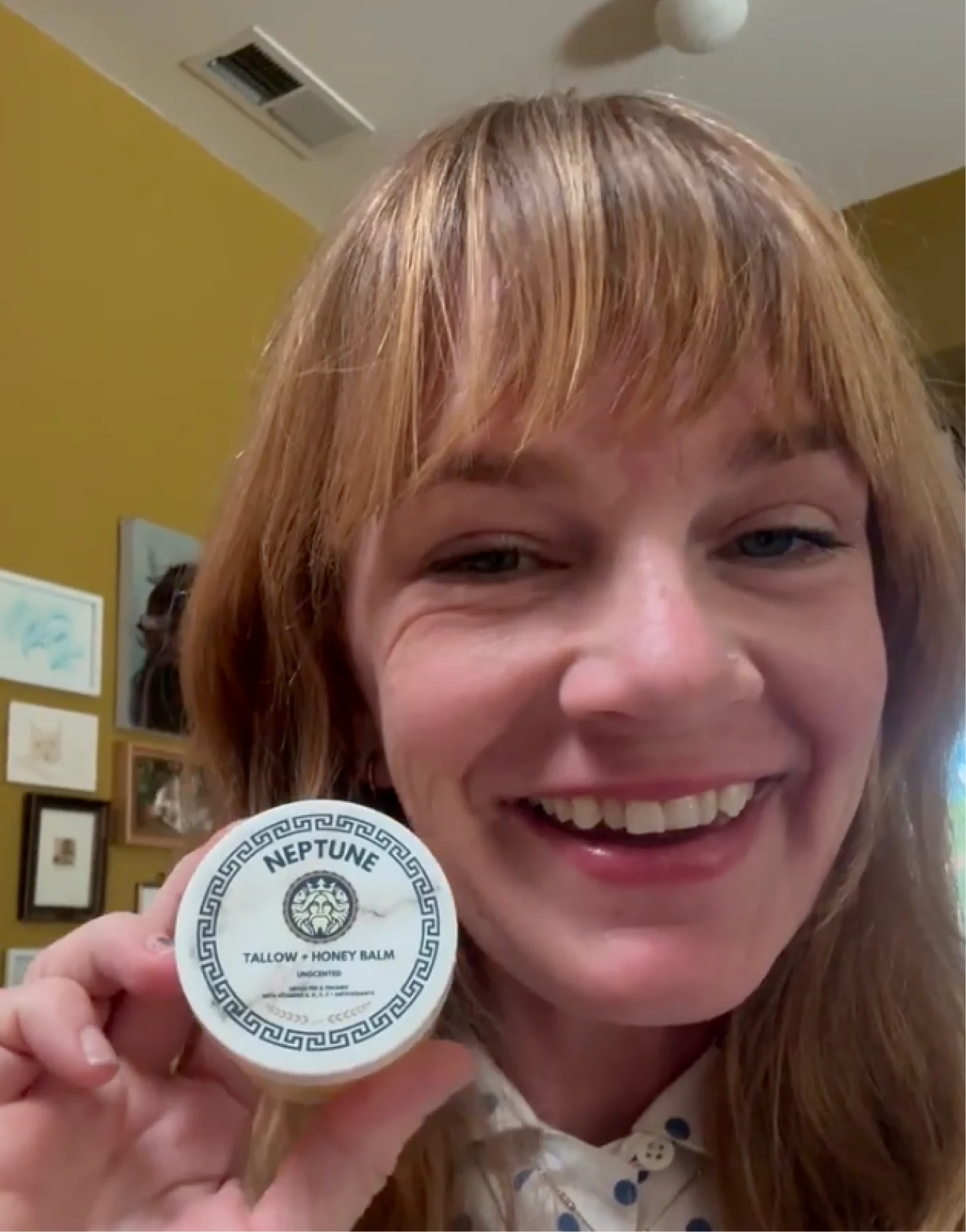 Person smiling while holding a container labeled 'Neptune Tallow Honey Balm'.