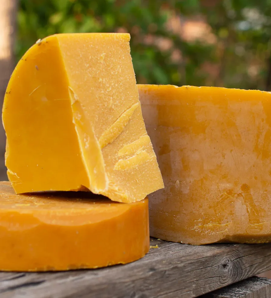 Large blocks of yellowish-brown wax on a wooden surface.