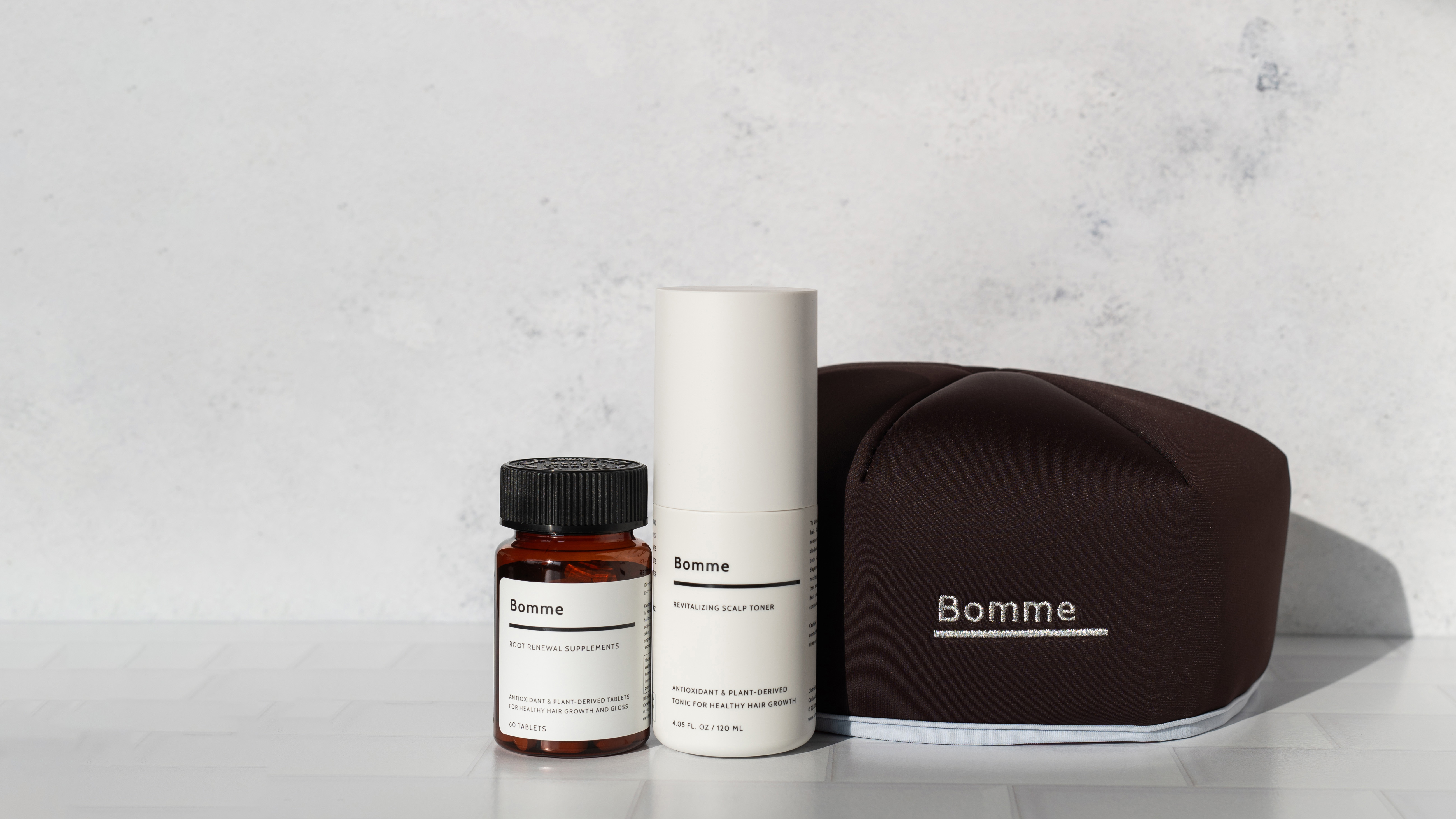 Three Bomme hair care products on a white surface.