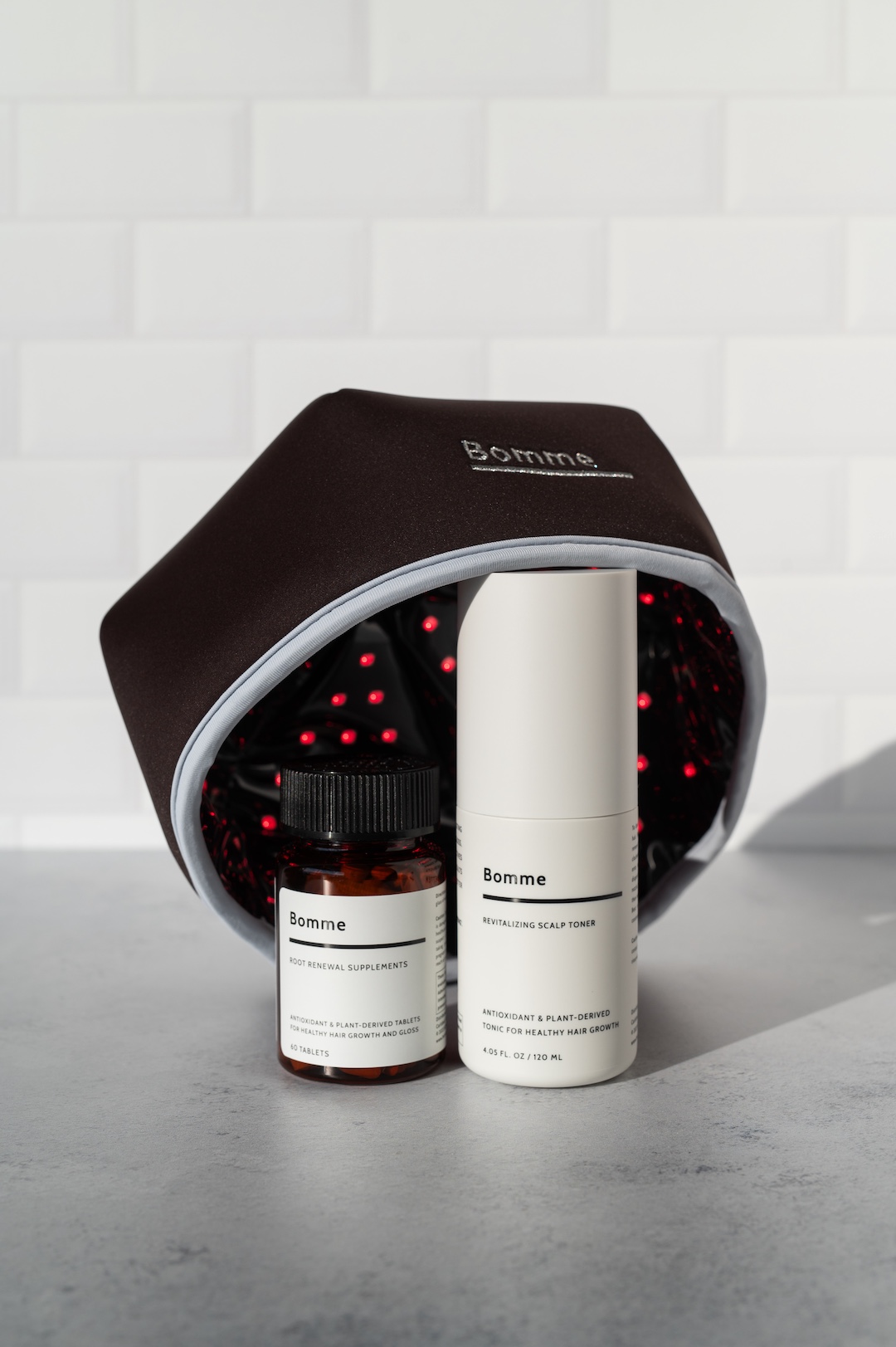 Hair care products with a black cap and two bottles on a tiled background.