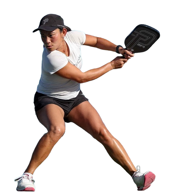 A female pickleball player in a white shirt and black cap swings her paddle during a match.
