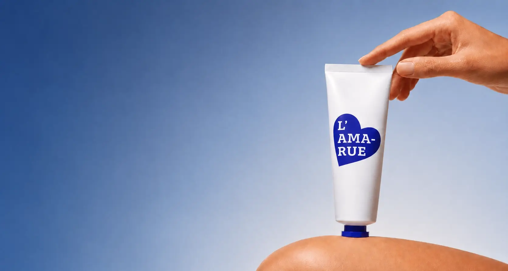 A hand holds a white tube of L'AMA-RUE cream, resting it on a person's skin against a blue background.