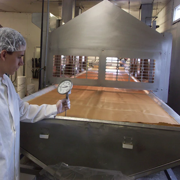 Person in a lab coat checking machinery with a temperature gauge.