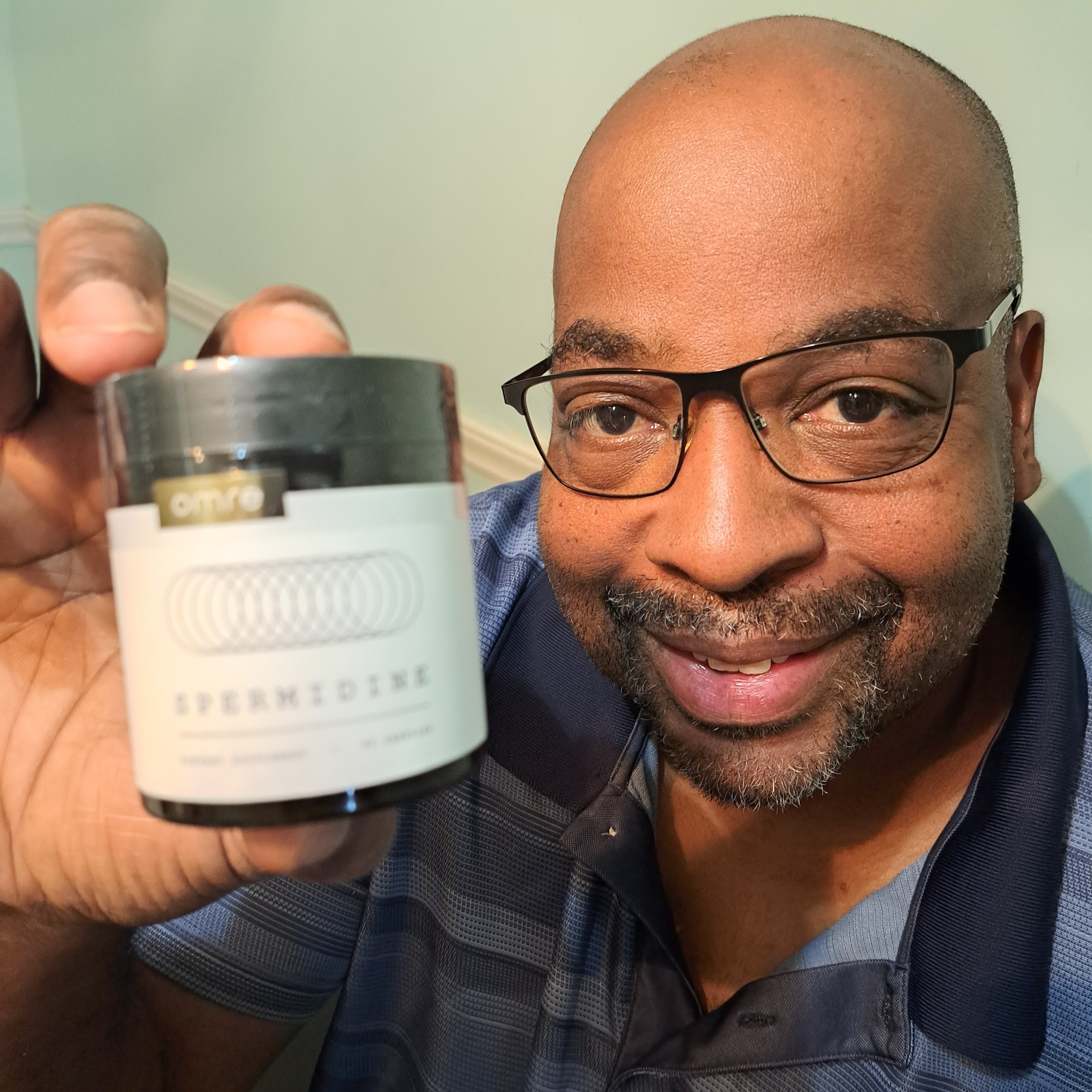Man holding a container labeled 'Spermidine' and smiling at the camera.