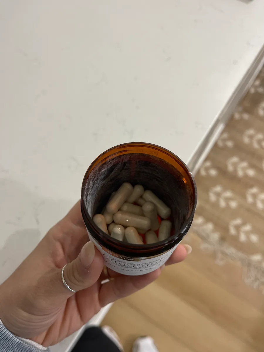 Hand holding a brown bottle filled with capsules.