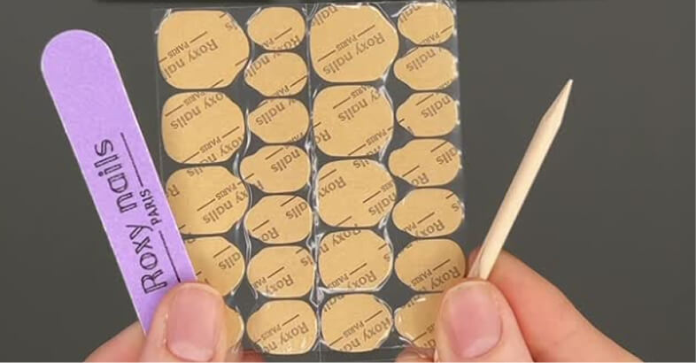 Nail care kit with wooden stick, file, and adhesive tabs.