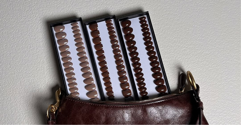 Three trays of brown nail tips in a leather bag.