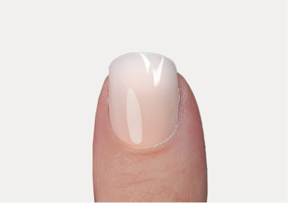 Close-up of a thumb with glossy, light-colored nail polish.