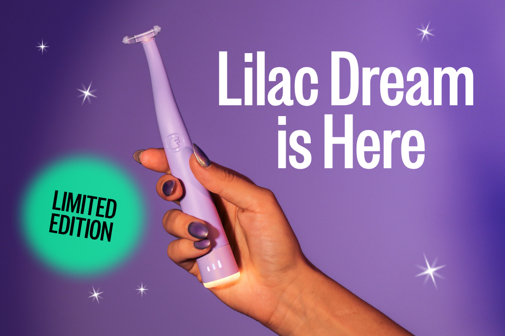 A hand with purple nails holds a lilac electric facial tool against a purple, sparkly background.