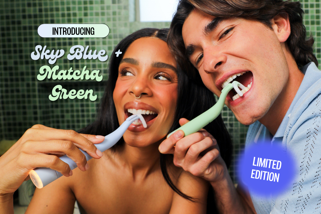 A woman and a man smile while using light blue and light green dental cleaning devices.