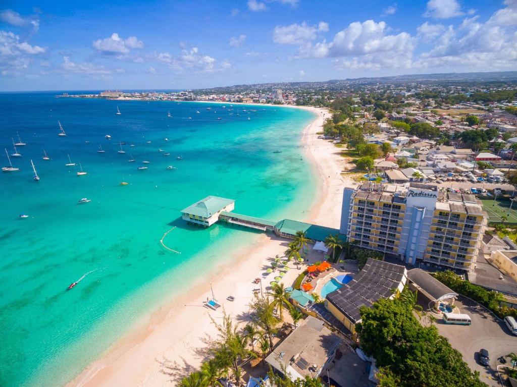 Aerial view of a Radisson hotel on a tropical beach with turquoise water and many sailboats.