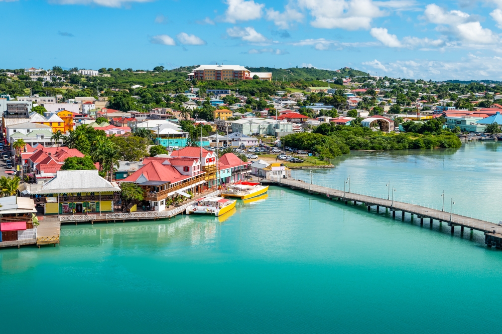 An aerial view of a colorful tropical port town with a pier extending into turquoise water.