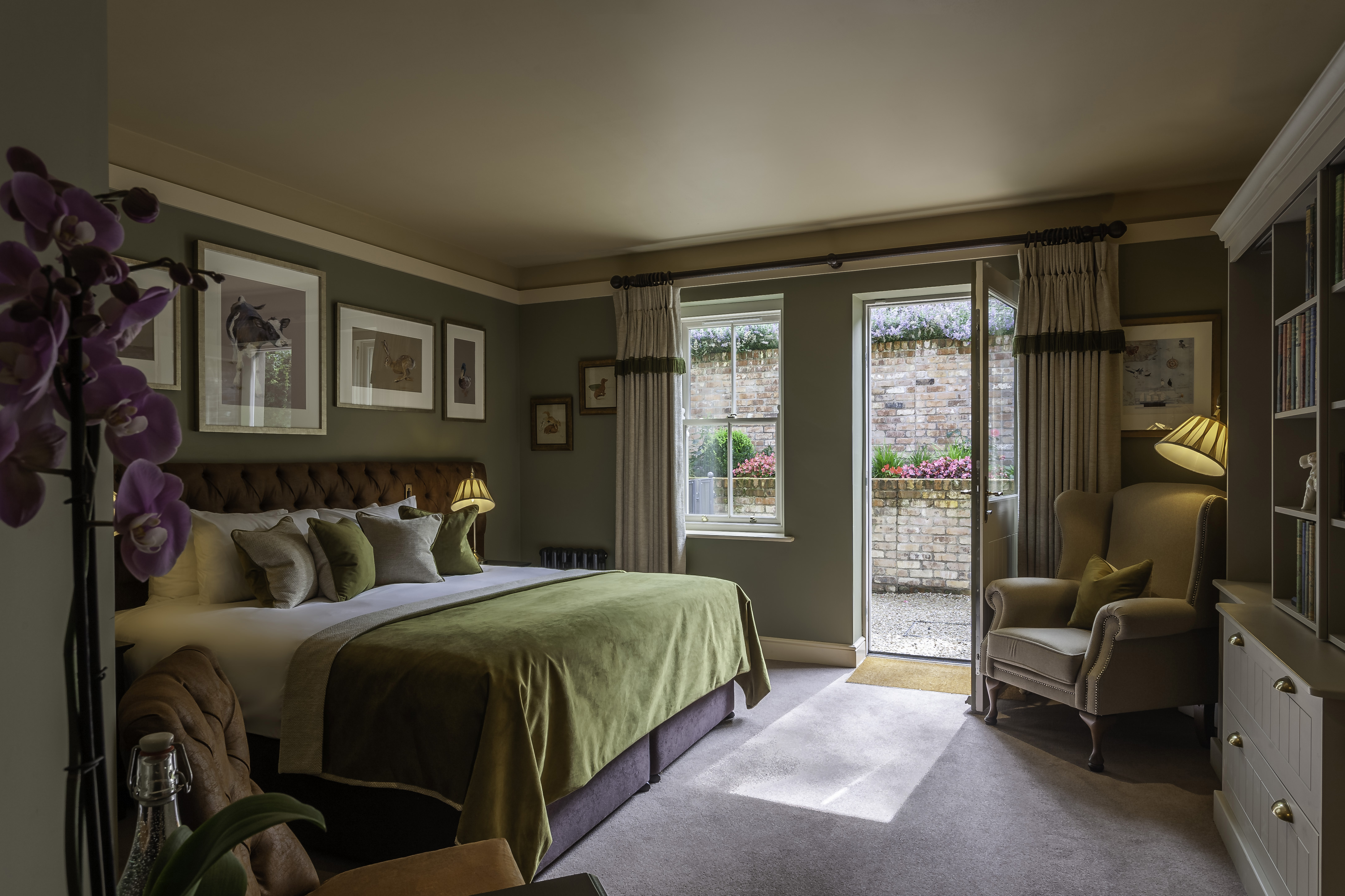 Cozy bedroom with green accents, armchair, and open door to garden.