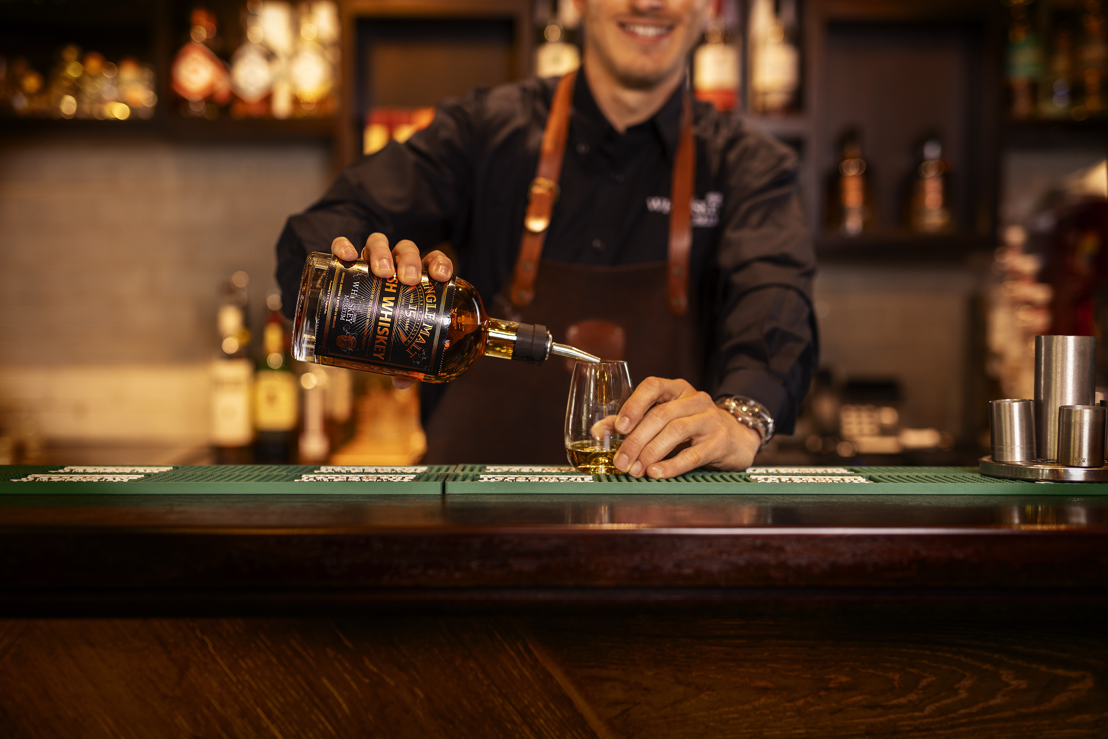 Bartender pouring whiskey into a glass at a bar.