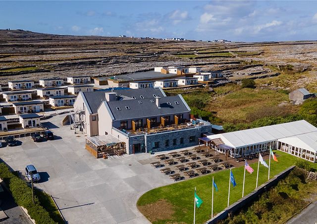 Aerial view of a large building with flags and parking area nearby.