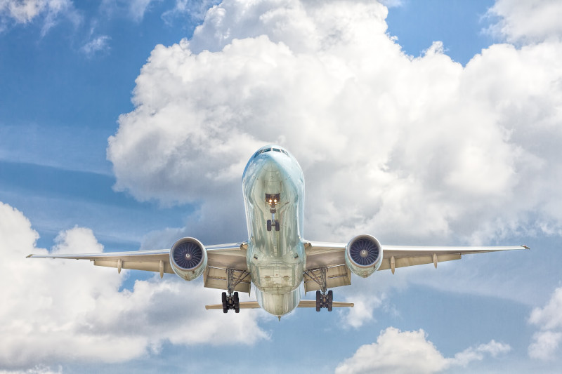 Airplane flying against a backdrop of fluffy clouds.