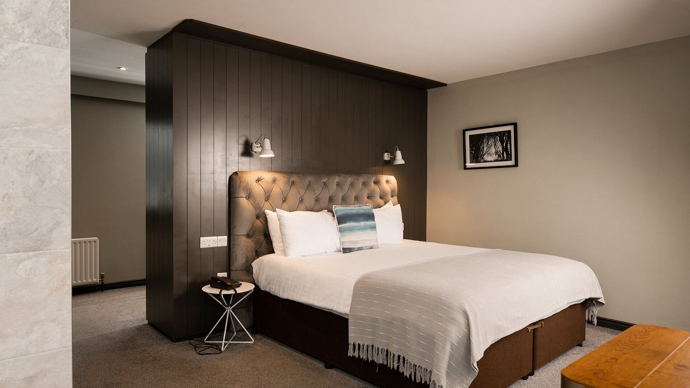 Modern bedroom with a double bed, wall lamps, and framed artwork.