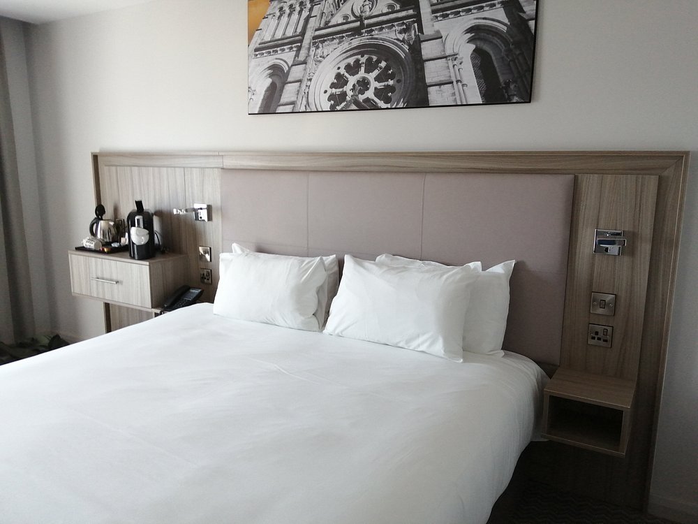 Hotel room with a neatly made bed and a black-and-white photo above the headboard.