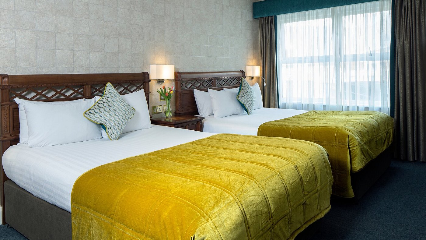 Two double beds with yellow covers in a hotel room.