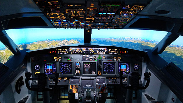 Airplane cockpit with illuminated controls and a scenic view outside.