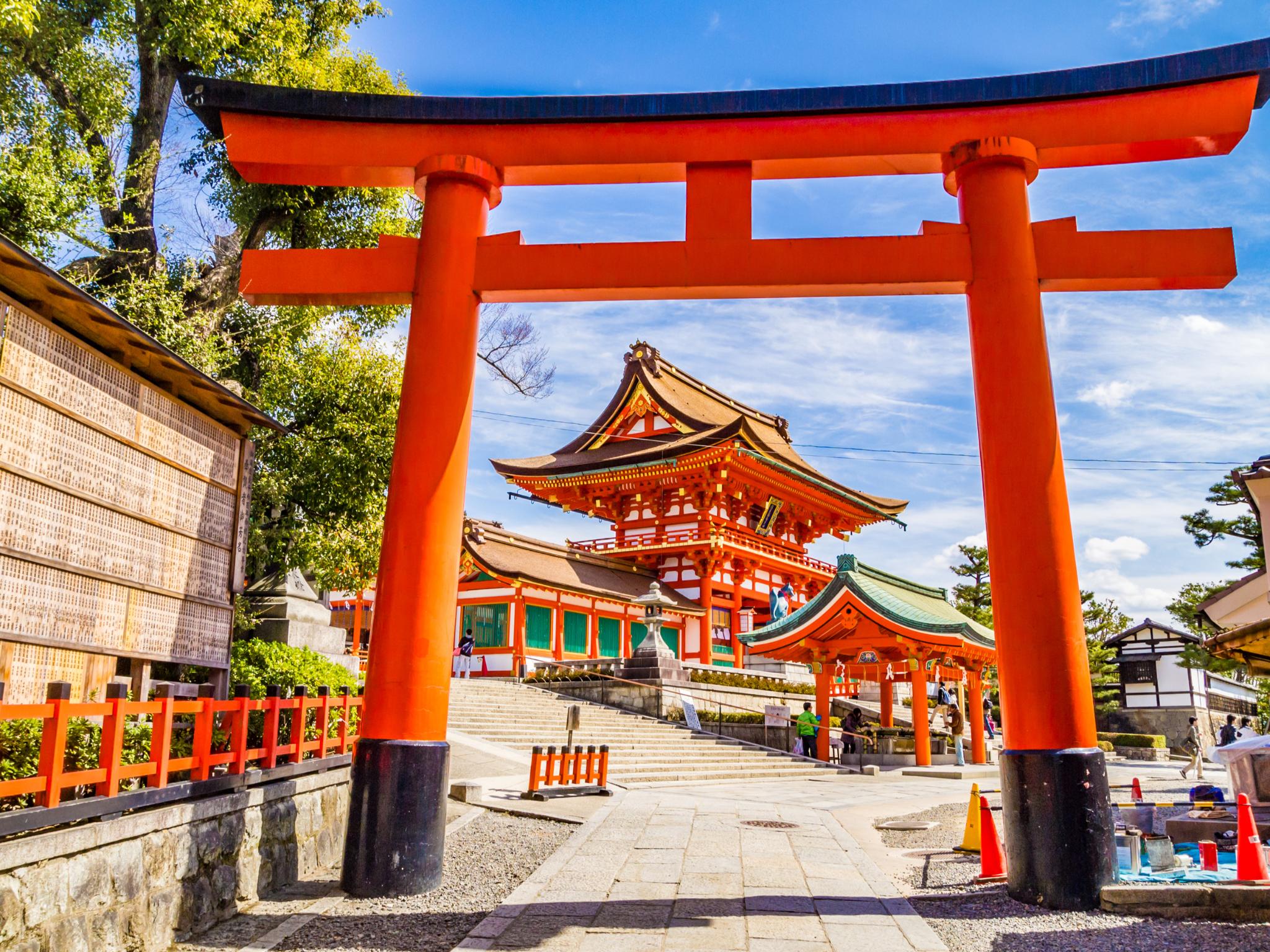 Red torii gate leading to a traditional Japanese shrine.