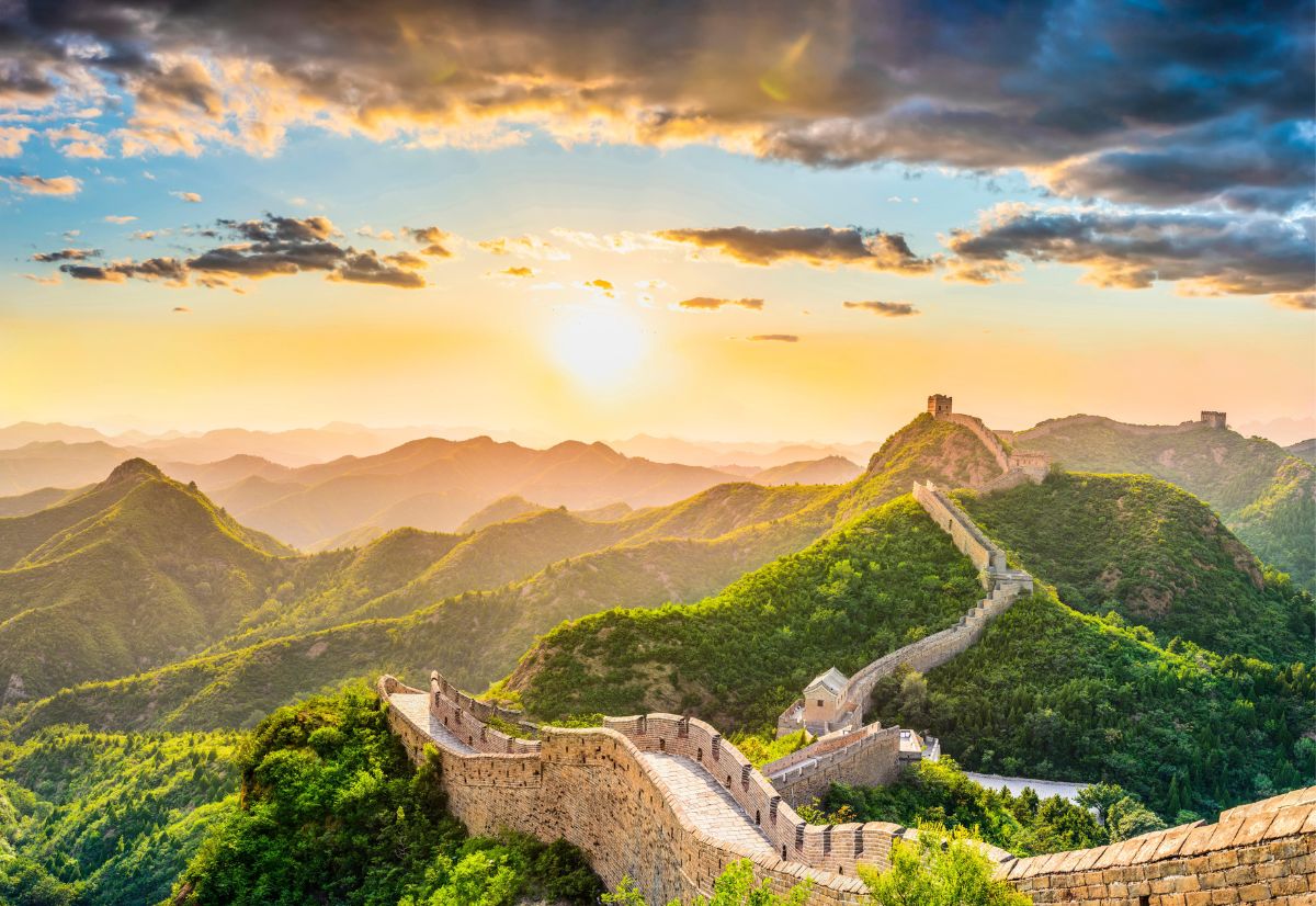 Great Wall of China at sunset with mountains in the background.