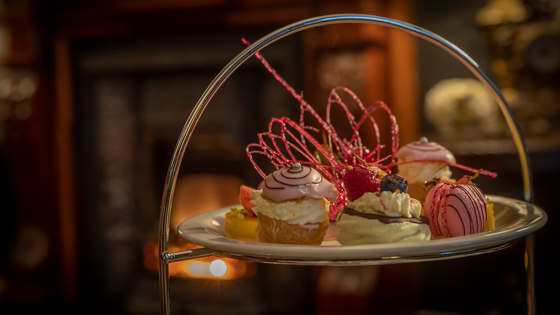Elegant dessert platter featuring pastries and macarons with decorative sugar work.