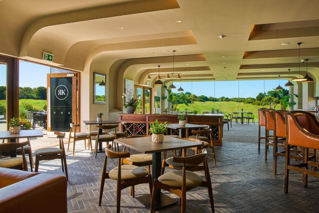 The interior of a modern restaurant with large windows that look out onto a green golf course.