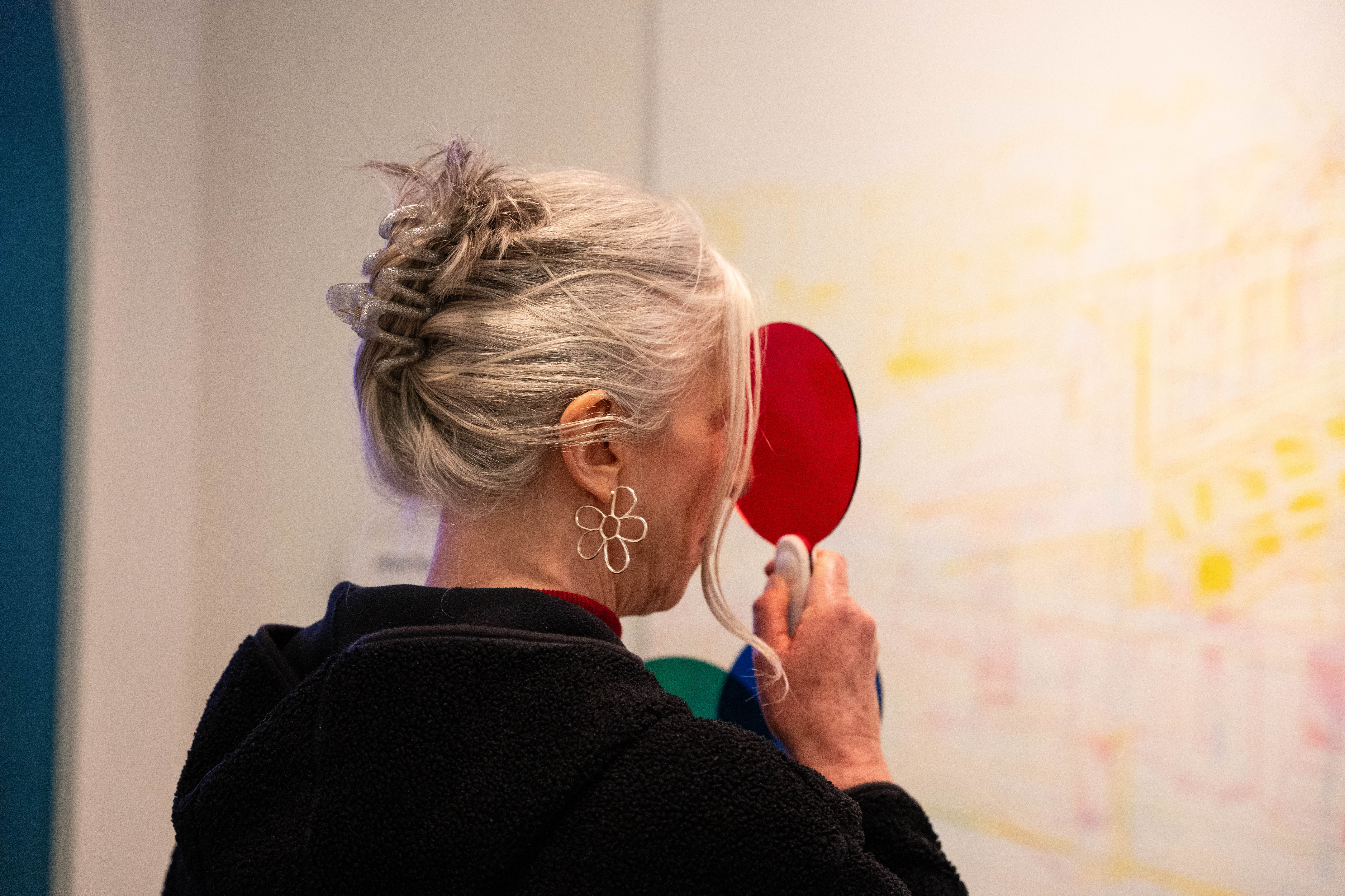 Person holding a red circular object, viewed from behind.