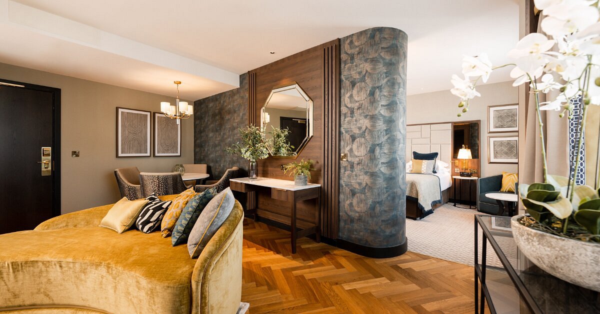 Luxurious hotel suite with elegant decor, seating area, and bed.
