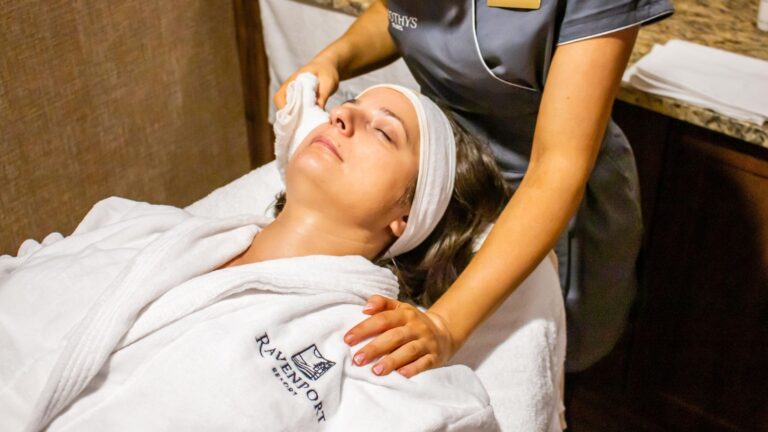 Person receiving a facial treatment at a spa, wearing a white robe.