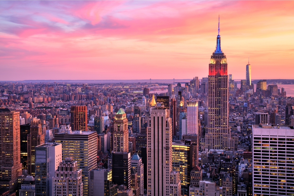 An aerial view of the New York City skyline, including the Empire State Building, at sunset.