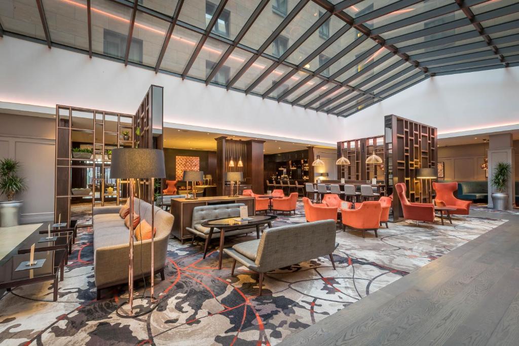 Spacious hotel lobby with modern furniture and large glass ceiling.