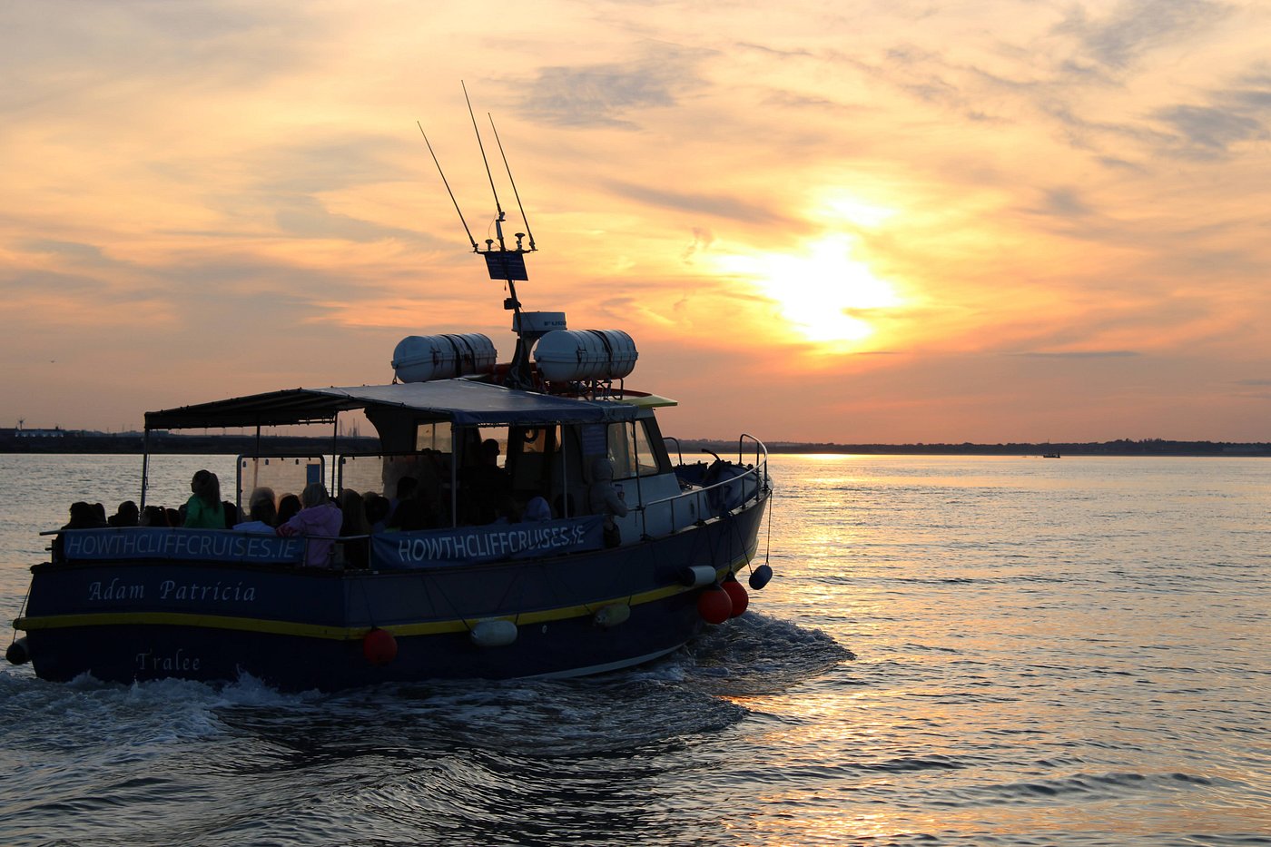 Boat with passengers on water at sunset.