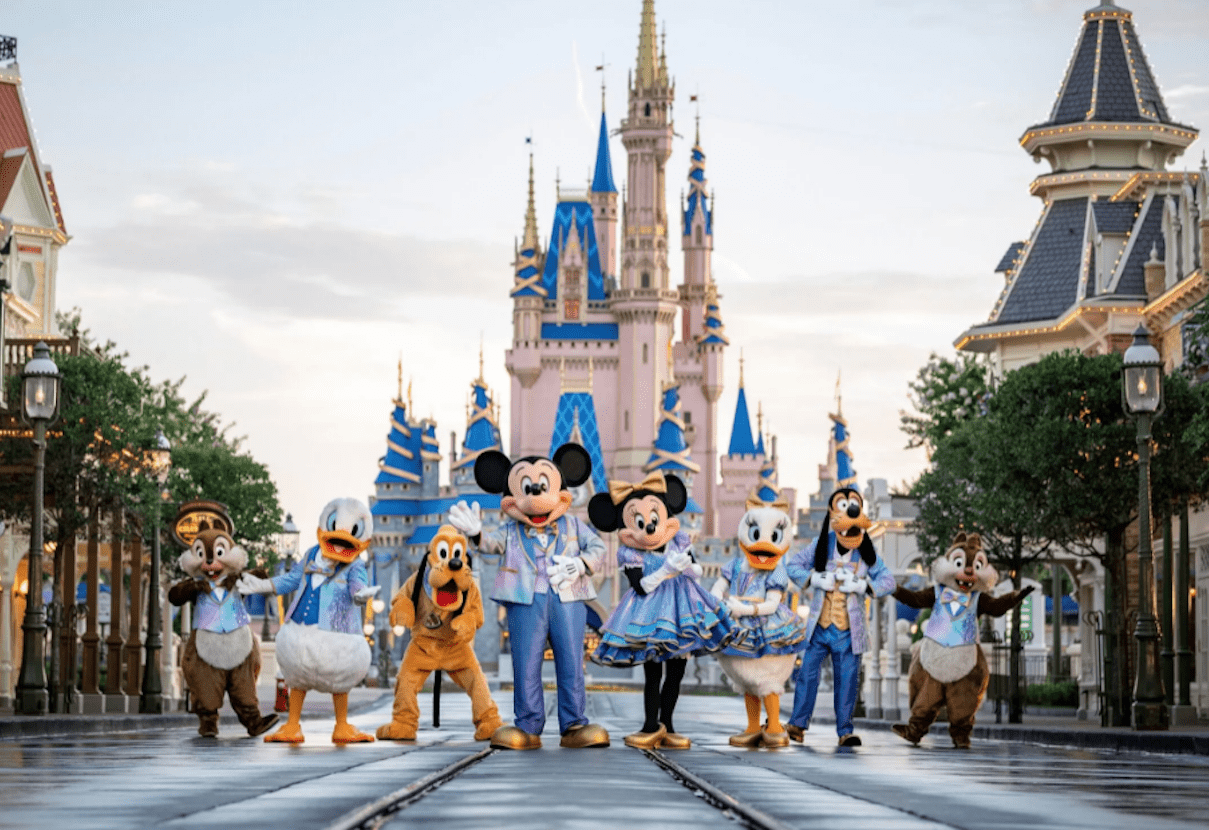Mickey Mouse and friends in iridescent outfits posing on Main Street in front of Cinderella's Castle.