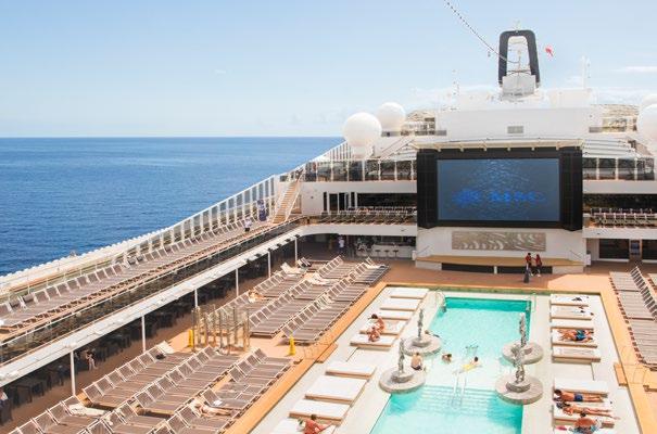 Cruise ship deck with pool, sun loungers, and large screen.