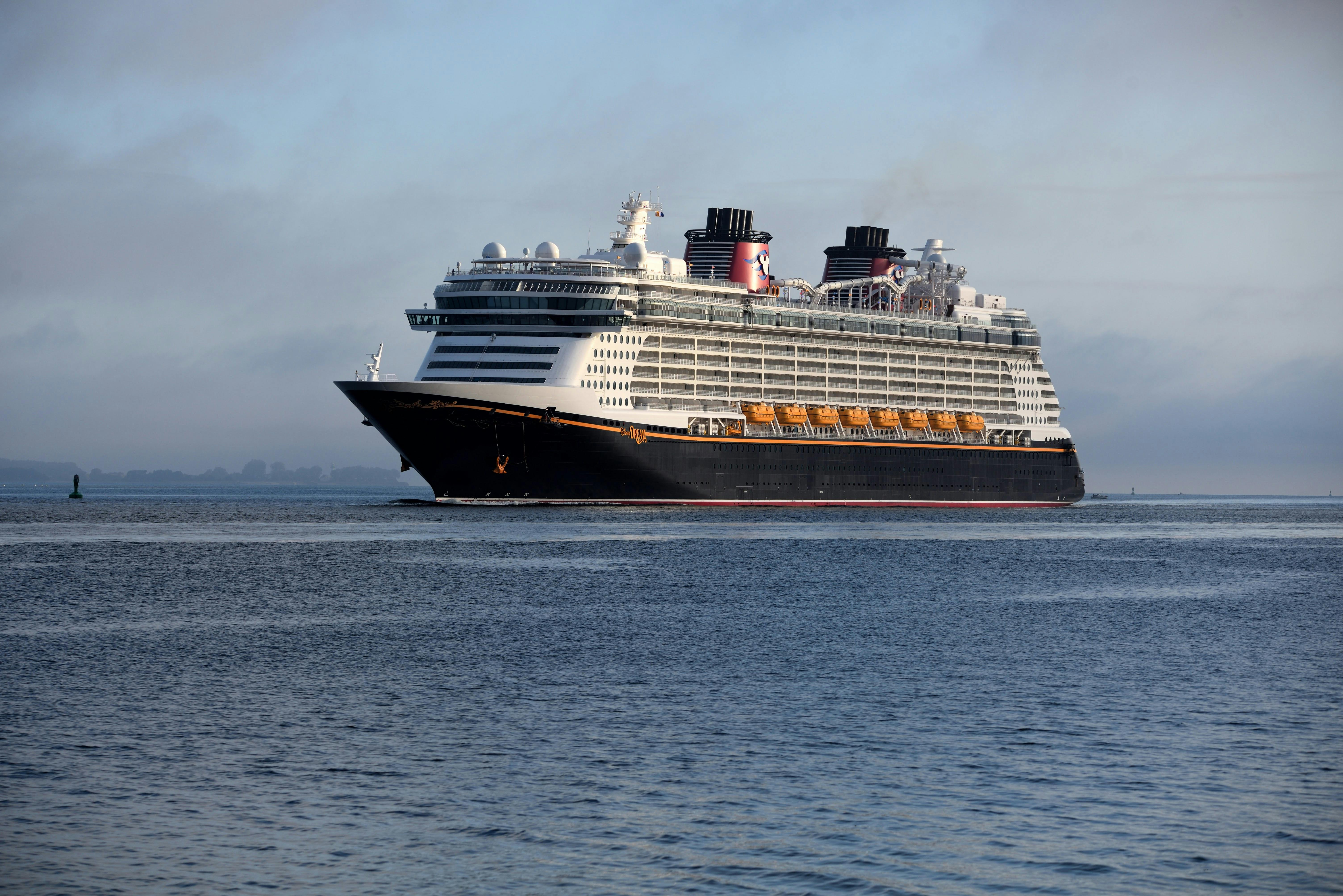 The Disney Dream cruise ship sailing on the open water under a hazy sky.
