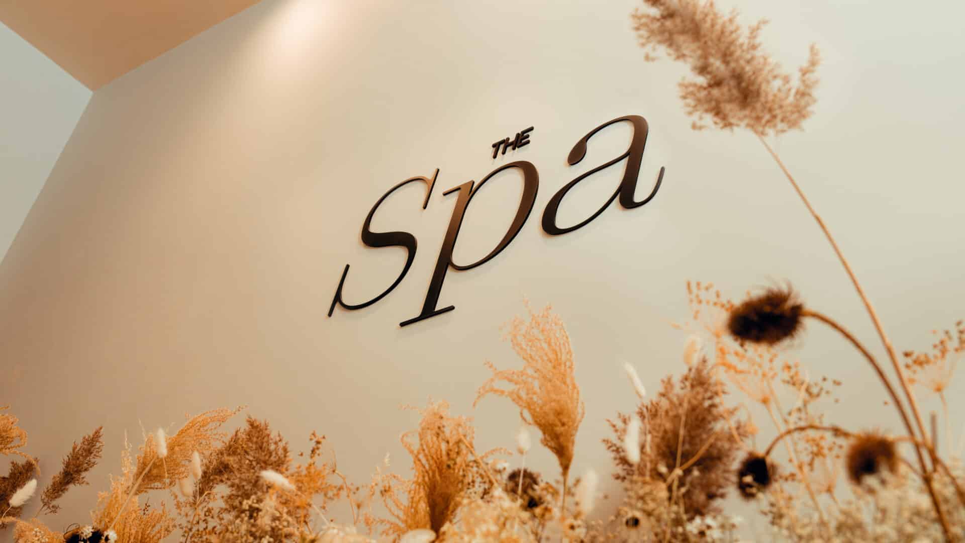 'The word 'spa' on a wall with decorative dried plants.'
