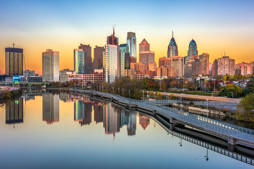 The Philadelphia skyline with skyscrapers reflected in the Schuylkill River at sunset.