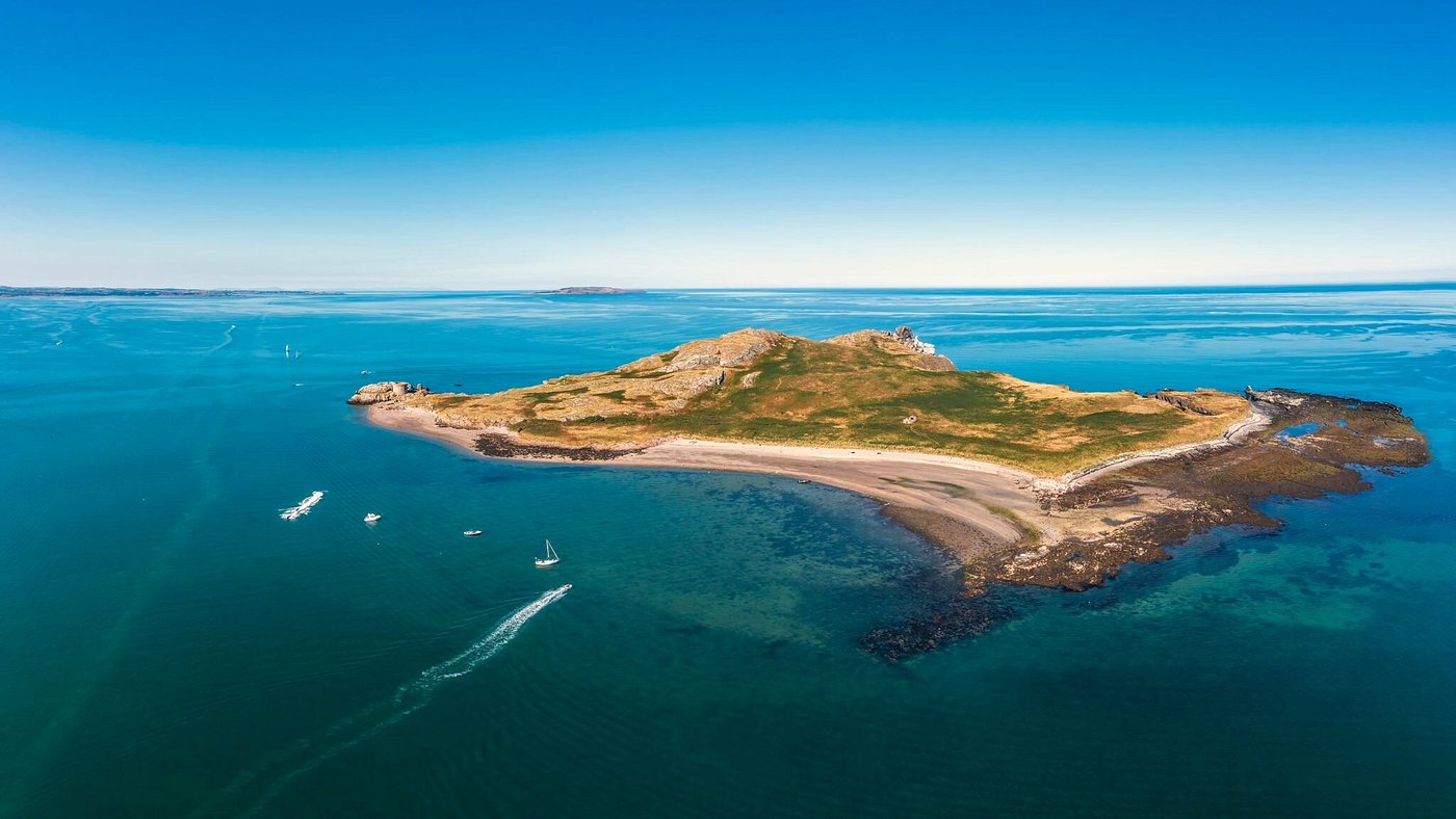 Aerial view of a small island with green hills and surrounding blue ocean.