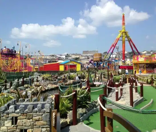 Amusement park with rides, pathways, and colorful buildings under a blue sky.