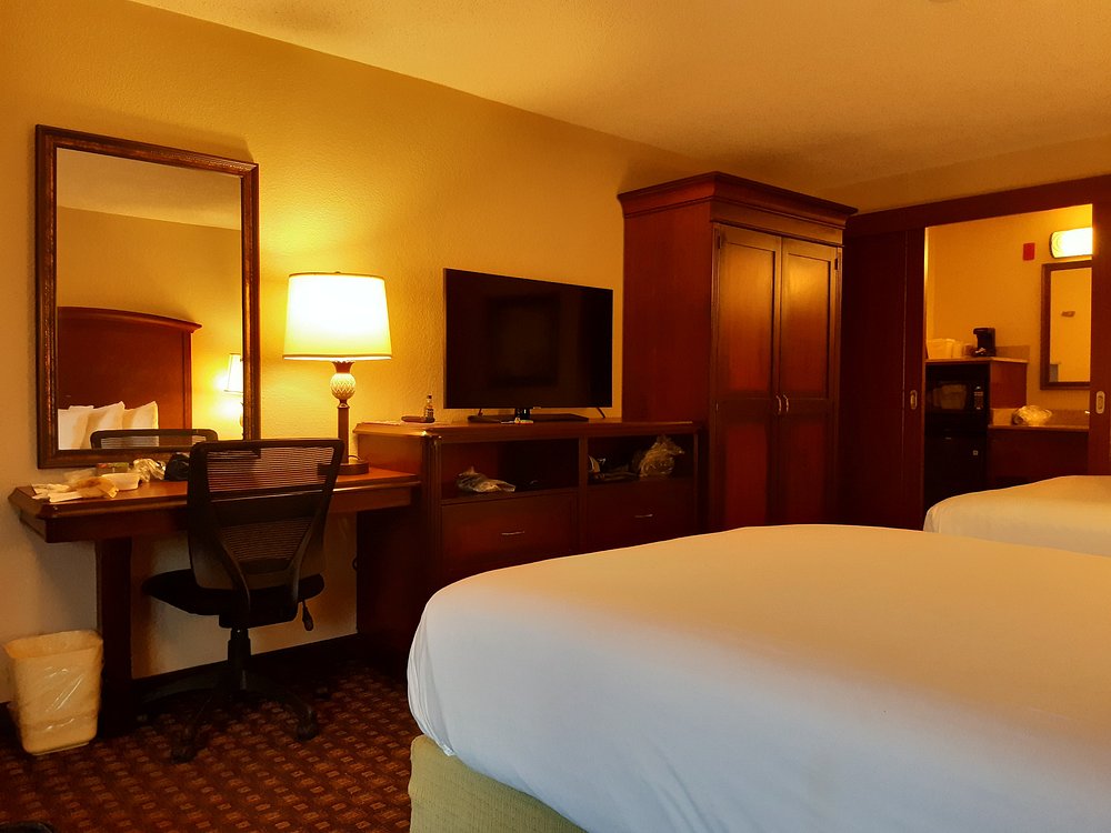 Hotel room with beds, desk, chair, TV, and wardrobe.
