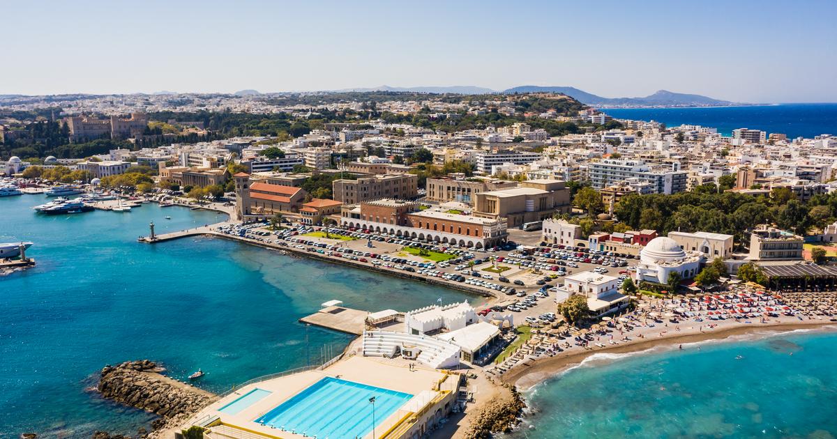 Aerial view of a coastal city with a beach, buildings, and a swimming pool.