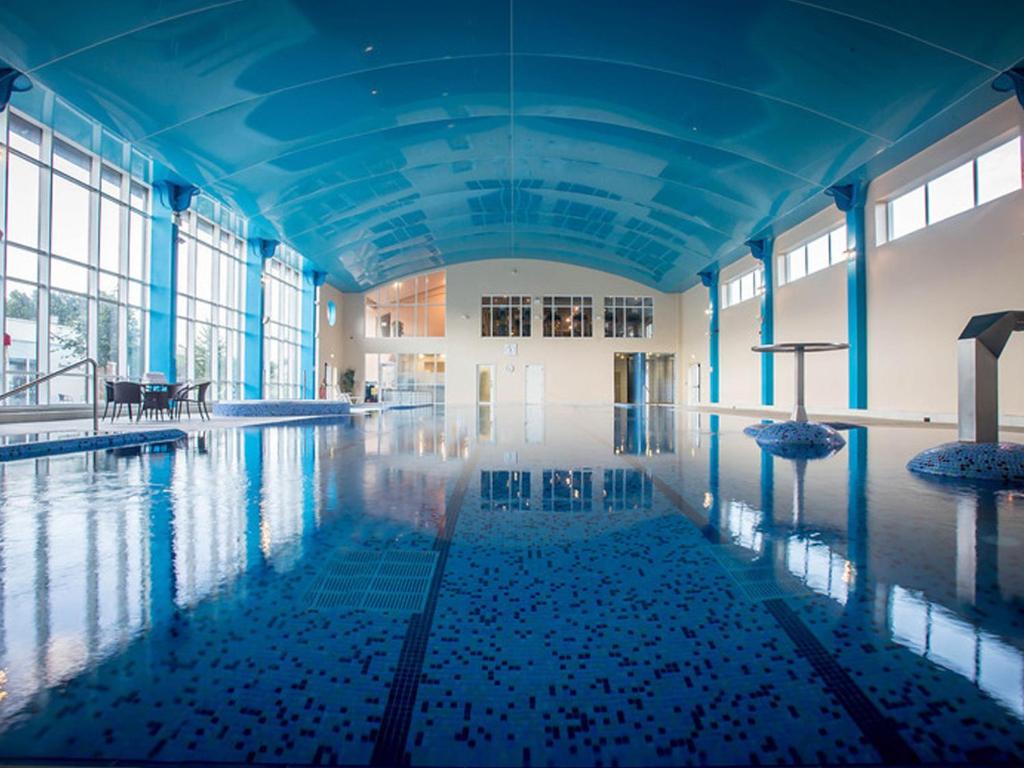 Indoor swimming pool with blue ceiling and large windows.